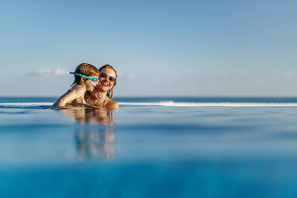 istock Happy boy having fun with his single mother in the pool. 2233622300