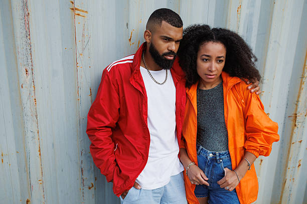 istock Stylish black man hugging girlfriend in windbreaker jacket near cargo container 2233622418