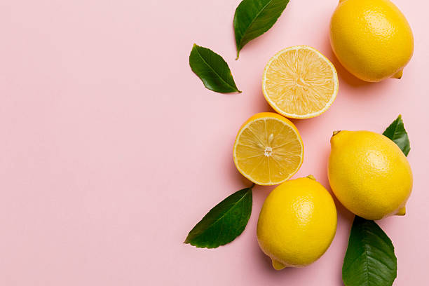 istock Many fresh ripe lemons with green leaves on colored background, top view, space for text 2233624052