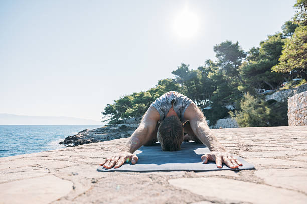 istock Man Practicing Yoga Stretch Outdoors by Sea 2233625166