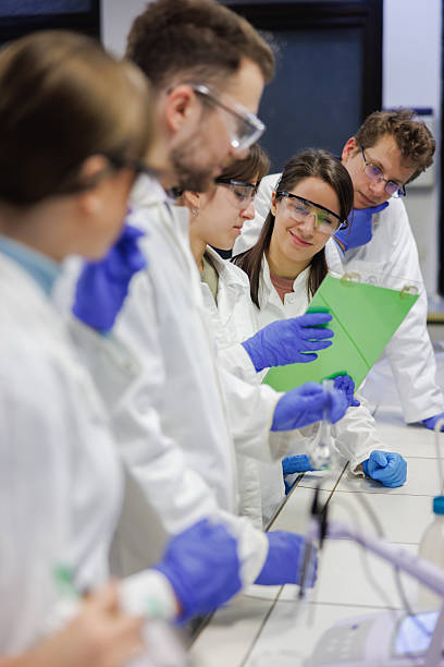 istock Group of students in faculty lab, wearing lab coats and surgical gloves in practical class 2233626618