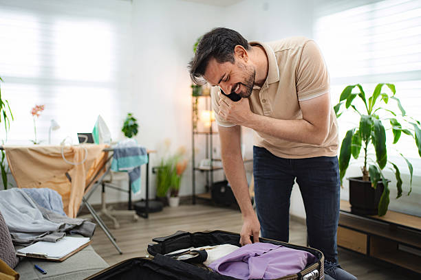 istock Man talking on the phone while packing his suitcase at home 2233627126