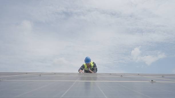 istock Solar technician inspecting physical damage on solar panels and coordinating with coworker via walkie-talkie at solar farm 2233633740