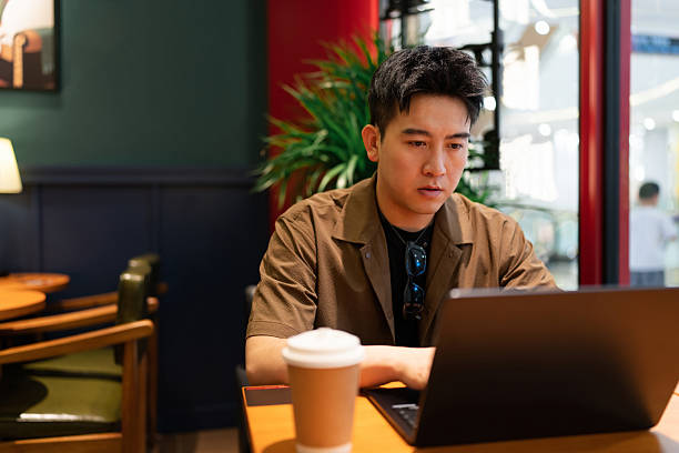 istock Asian handsome man using laptop in coffee shop 2233635439
