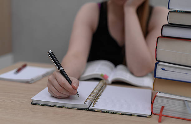 istock A student is doing her homework for school, overwhelmed with books and studying 2233637188