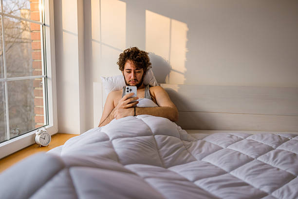 istock Bearded man lying in bed staring at smartphone screen 2233641687