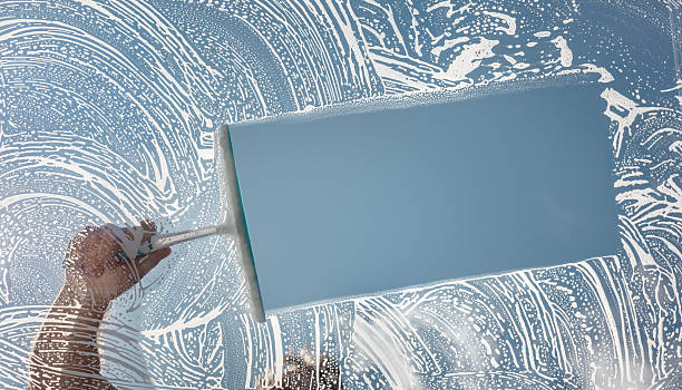 istock Window cleaner using a squeegee to wash and clean a window 2233641708