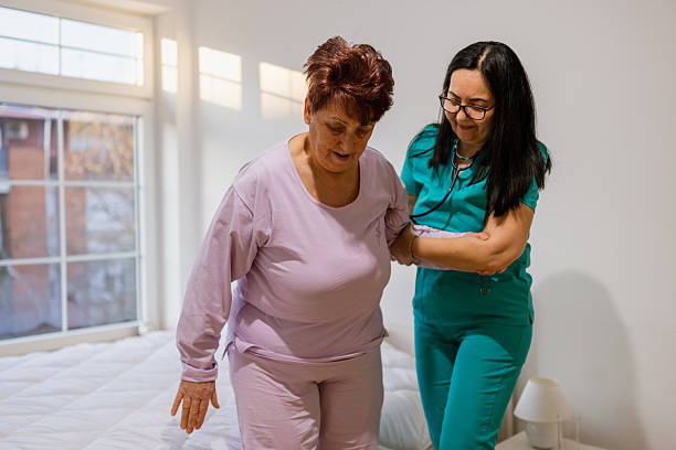 istock Nurse assisting patient to get up from bed in nursing home 2233642920