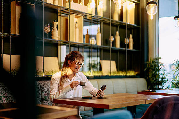 istock Young Woman Enjoying Coffee While Using Her Smartphone in a Cozy Restaurant 2233643506