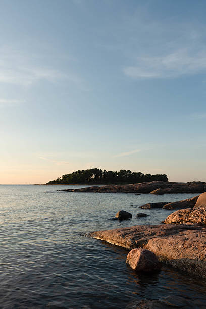 istock Rocky coast with calm sea and forested island. 2233644267