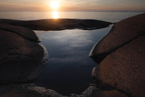 Golden sunset reflecting in a narrow rocky crevice filled with seawater. A dramatic and peaceful coastal detail that captures the essence of nature’s textures and light. Perfect for travel, environmental themes, inspirational designs, and editorial use.