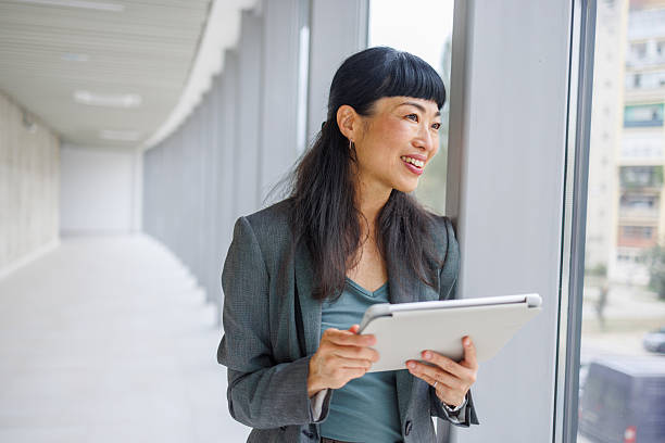 istock Businesswoman smiling and using digital tablet in modern office 2233644736