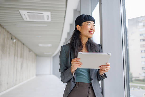 istock Businesswoman holding digital tablet looking out office window 2233644768