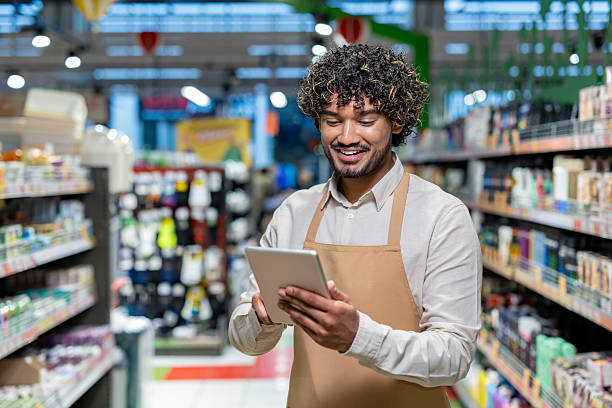 istock An employee in a grocery store smiles while checking inventory on a tablet. 2233645480