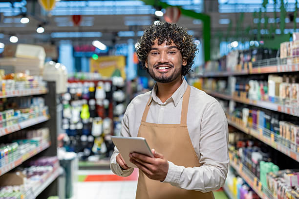 istock A cheerful grocery store employee smiles while using a tablet in the shop. 2233645481