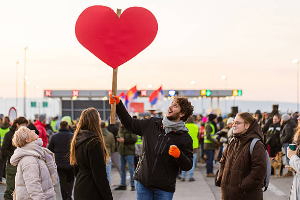 Group of cheerful friends holding big red heart sign while celebrating at pride event, symbolizing love, equality, and support for LGBT community at border pass