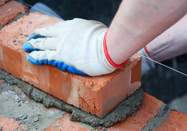 istock A builder laying brick on cement mortar during house construction. Bricklaying closeup. 2233649514