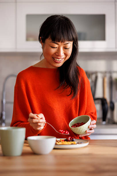 istock Woman adding berries to waffles while having breakfast at home 2233649932
