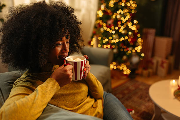 istock Young Woman Enjoying Hot Cocoa by Christmas Tree 2233651157