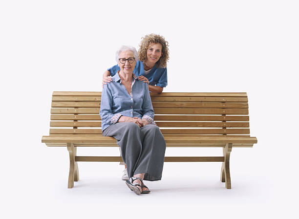 istock Senior lady sitting on a bench and caregiver 2233651424