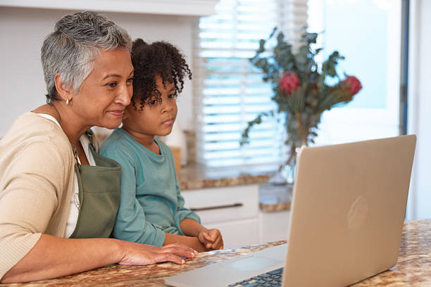 istock Mom or Grandma Sitting with son at Computer in Kitchen 2233654289