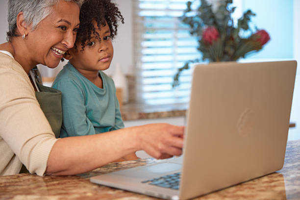 istock Mom or Grandma Sitting with son at Computer in Kitchen 2233654366