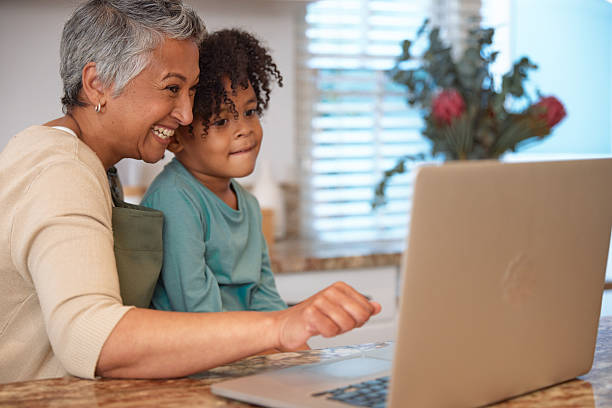 istock Mom or Grandma Sitting with son at Computer in Kitchen 2233654368