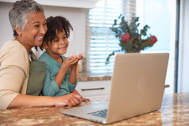 istock Mom or Grandma Sitting with son at Computer in Kitchen 2233654393