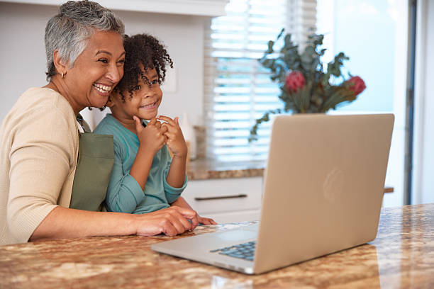 istock Mom or Grandma Sitting with son at Computer in Kitchen 2233654404