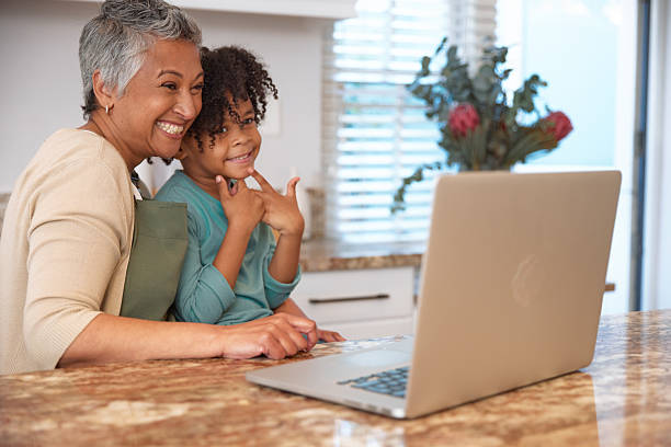 istock Mom or Grandma Sitting with son at Computer in Kitchen 2233654409