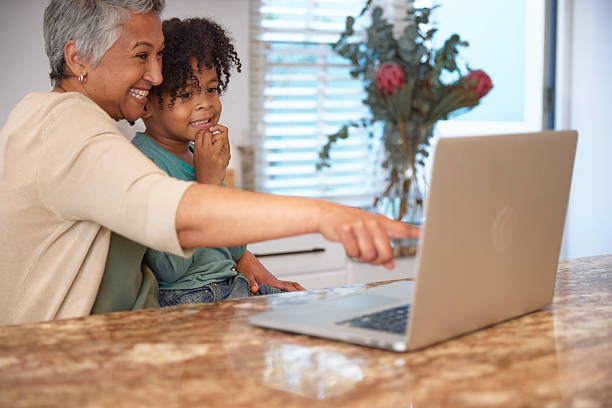 istock Mom or Grandma Sitting with son at Computer in Kitchen 2233654414