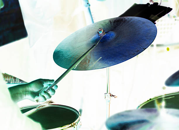 A musician playing drums, focusing on a hand striking a cymbal with a drumstick.
