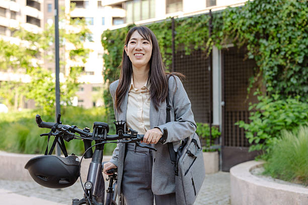 istock Professional woman commuting to work with a bicycle in urban greenery 2233658476