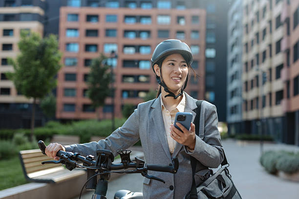istock Professional woman commuting on electric bike while using smartphone outside corporate building 2233659259