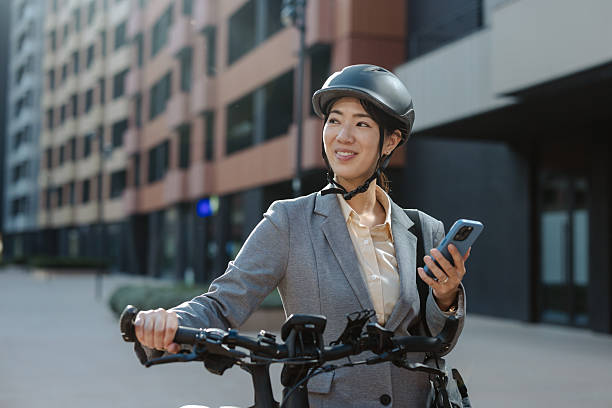 istock Professional woman commuting on electric bike while using smartphone outside corporate building 2233659276