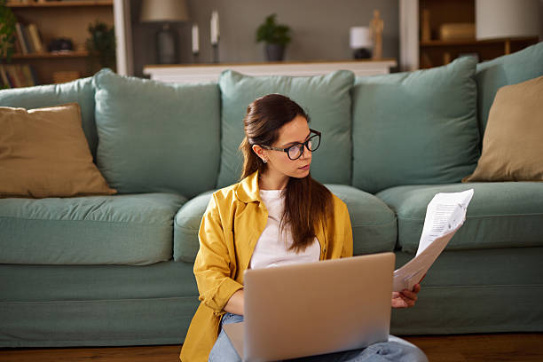 istock Focused young woman working from home managing finances on laptop 2233663258