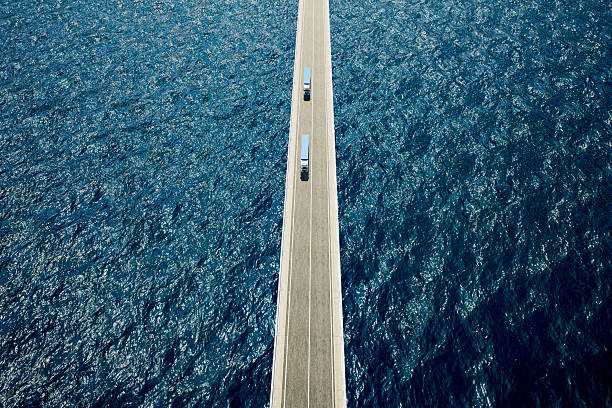 istock Two blue freight trucks on bridge over the ocean 2233664149