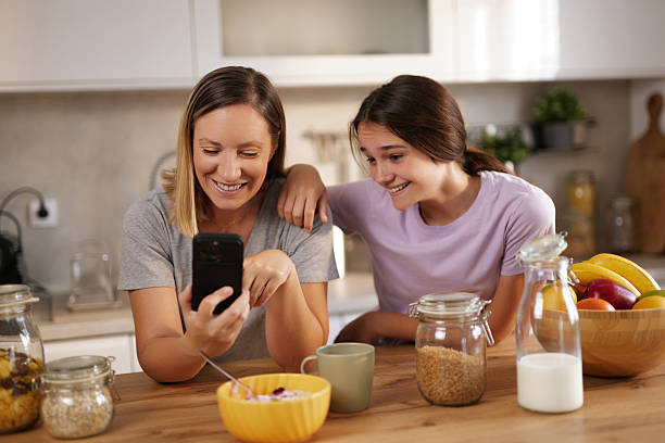 istock Mother and daughter enjoying breakfast and browsing smartphone together in kitchen 2233664768