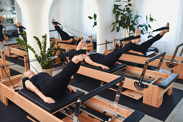 istock Women Practicing Pilates Reformer Exercises Together In Modern Studio 2233667110