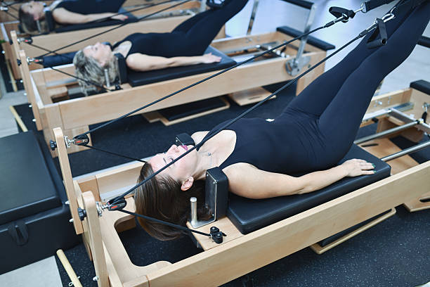 istock Synchronized Female Pilates Practitioners Engaged In Group Reformer Training 2233667374