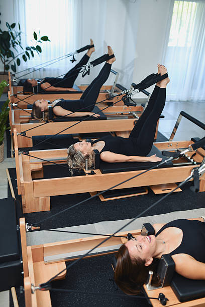 istock Fit Women Performing Challenging Pilates Reformer Exercises In Unison 2233667395