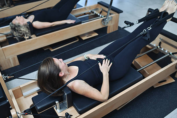 istock Group Of Women Practicing Pilates On Reformers In Perfect Synchronization 2233667466