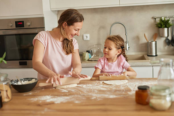 istock Mother and daughter making dough in kitchen together 2233669712