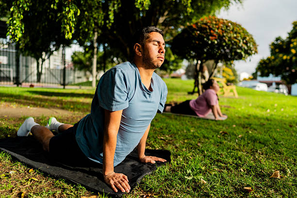 Young man with developmental disablity doing yoga on the public park