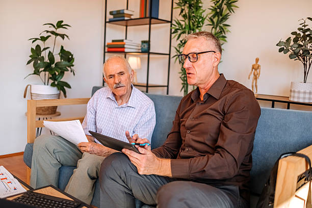 istock Businessman with finance occupation working at clients home using digital tablet so he can explain better where to invest savings 2233675010
