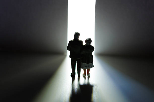 istock Elderly couple walking away towards light through open door 2233677014