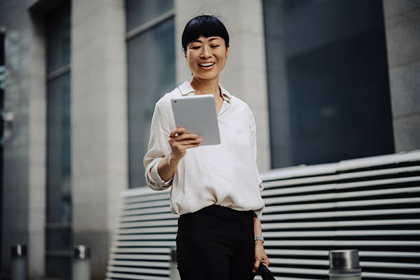 istock Japanese Businesswoman Using Tablet While Walking to Work with Laptop Bag 2233678065