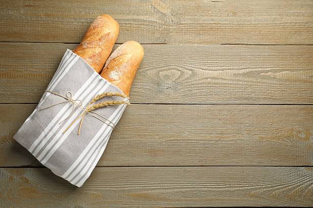 istock Fresh baguettes and spikes on wooden table, top view. Space for text 2233678135