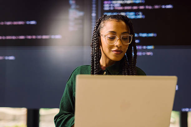 junger programmierer, der code auf laptop und großem bildschirm in modernem büro analysiert - programmierer stock-fotos und bilder