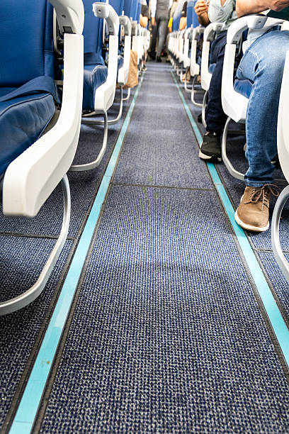 istock Airplane cabin carpeted floor with reflective and illuminated guide lines for evacuation during emergency 2233680750